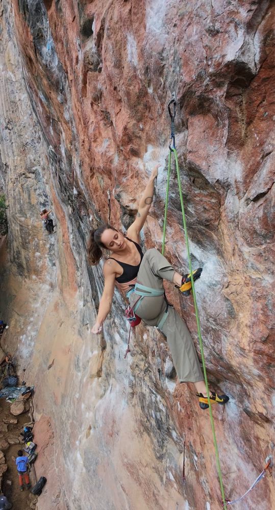 Luiza guiando uma via esportiva em parede avermelhada