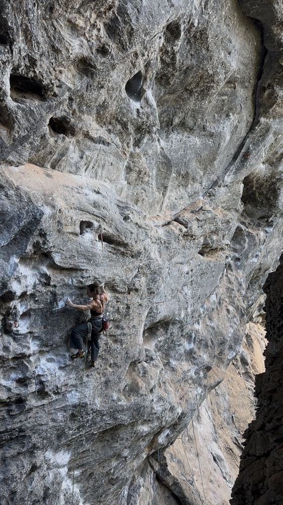Luiza escalando uma via esportiva em calcário cinza